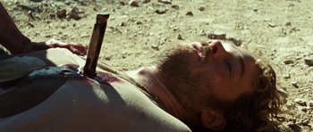 Movie still from “The Ruins” (2008), directed by Carter Smith – A man laying on the ground with a knife stuck in his head; Close Up shot, High angle
