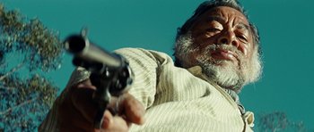 Movie still from “The Ruins” (2008), directed by Carter Smith – An old man holding a gun in his hand; Close Up shot, Low angle