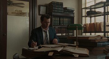 Movie still from “The Rum Diary” (2011), directed by Bruce Robinson – A man sitting at a desk writing on a piece of paper; Wide shot, High angle