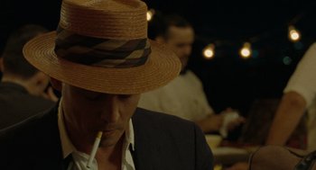 Movie still from “The Rum Diary” (2011), directed by Bruce Robinson – A man wearing a straw hat while smoking a cigarette; Close Up shot, Over the shoulder angle