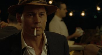 Movie still from “The Rum Diary” (2011), directed by Bruce Robinson – A person wearing a hat and smoking a cigarette; Close Up shot, Over the shoulder angle