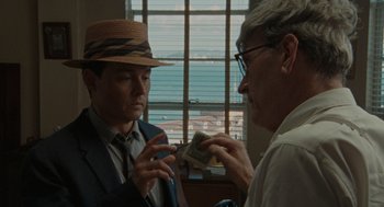 Movie still from “The Rum Diary” (2011), directed by Bruce Robinson – A man in a hat and a man in a suit holding a stack of money; Close Up shot, Over the shoulder angle