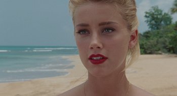 Movie still from “The Rum Diary” (2011), directed by Bruce Robinson – A beautiful young blond woman standing on top of a sandy beach; Close Up shot, Over the shoulder angle
