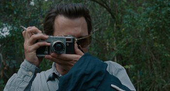 Movie still from “The Rum Diary” (2011), directed by Bruce Robinson – A man taking a picture with a camera; Close Up shot, Low angle