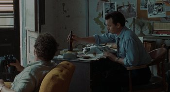 Movie still from “The Rum Diary” (2011), directed by Bruce Robinson – A man sitting at a table with a bottle of beer; Medium shot, High angle