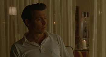 Movie still from “The Rum Diary” (2011), directed by Bruce Robinson – A man sitting in a chair in front of a window; Close Up shot, Over the shoulder angle
