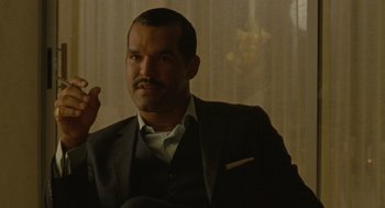 Movie still from “The Rum Diary” (2011), directed by Bruce Robinson – A man in a black suit and a white shirt; Close Up shot, Over the shoulder angle