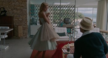 Movie still from “The Rum Diary” (2011), directed by Bruce Robinson – A woman in a dress standing in a living room; Wide shot, Low angle