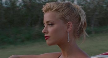 Movie still from “The Rum Diary” (2011), directed by Bruce Robinson – A beautiful blonde woman with red lipstick and earrings; Close Up shot, Over the shoulder angle