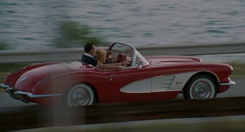 Movie still from “The Rum Diary” (2011), directed by Bruce Robinson – A man and a woman driving a red car; Wide shot, High angle