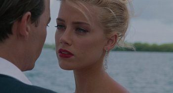 Movie still from “The Rum Diary” (2011), directed by Bruce Robinson – A beautiful blonde woman with red lipstick and earrings; Close Up shot, Over the shoulder angle