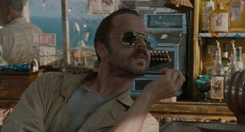 Movie still from “The Rum Diary” (2011), directed by Bruce Robinson – A man with a beard wearing sunglasses and a tan jacket; Close Up shot, Low angle