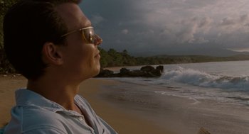 Movie still from “The Rum Diary” (2011), directed by Bruce Robinson – A man with sunglasses on a beach near the ocean; Close Up shot, Low angle