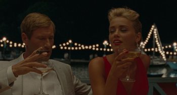 Movie still from “The Rum Diary” (2011), directed by Bruce Robinson – A man and a woman sitting at a table drinking champagne; Medium shot, Over the shoulder angle