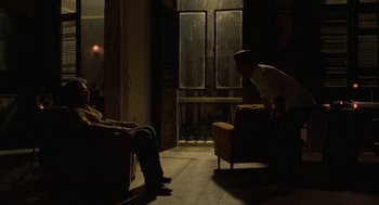 Movie still from “The Rum Diary” (2011), directed by Bruce Robinson – Two people sitting in a dark room looking out a window; Wide shot, Over the shoulder angle