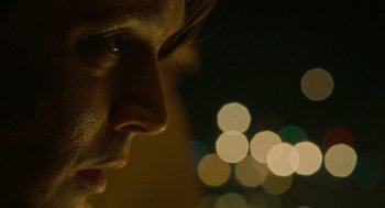 Movie still from “The Rum Diary” (2011), directed by Bruce Robinson – A man's face in front of blurry lights; Extreme Close Up shot, Over the shoulder angle