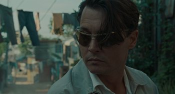 Movie still from “The Rum Diary” (2011), directed by Bruce Robinson – A man wearing sunglasses and a white shirt; Close Up shot, Low angle