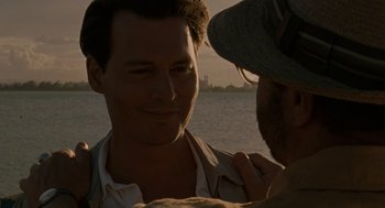 Movie still from “The Rum Diary” (2011), directed by Bruce Robinson – A man standing next to another man near a body of water; Close Up shot, Over the shoulder angle