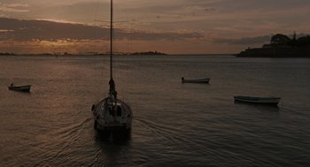 Movie still from “The Rum Diary” (2011), directed by Bruce Robinson – A sailboat in the water at sunset; Extreme Wide shot, Low angle