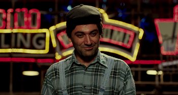 Movie still from “The Salesman” (2016), directed by Asghar Farhadi – A man in a plaid shirt wearing a hat and suspenders standing in front of a neon sign; Close Up shot, Over the shoulder angle
