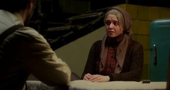 Movie still from “The Salesman” (2016), directed by Asghar Farhadi – A woman sitting in front of a man in front of a table; Medium shot, Over the shoulder angle