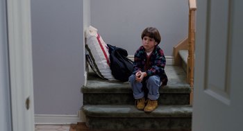Movie still from “The Santa Clause” (1994), directed by John Pasquin – A young boy sitting on the steps of a house; Medium shot, High angle