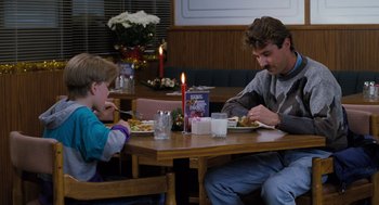 Movie still from “The Santa Clause” (1994), directed by John Pasquin – A man and a boy sitting at a dinner table; Medium shot, Over the shoulder angle