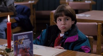 Movie still from “The Santa Clause” (1994), directed by John Pasquin – A young boy sitting at a table in front of a book; Close Up shot, High angle