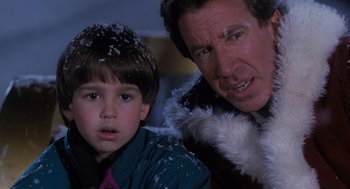 Movie still from “The Santa Clause” (1994), directed by John Pasquin – A man and a boy are standing next to each other in the snow; Close Up shot, High angle