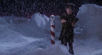 Movie still from “The Santa Clause” (1994), directed by John Pasquin – A young boy in a uniform standing in the middle of a snow covered field; Medium shot, High angle