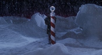 Movie still from “The Santa Clause” (1994), directed by John Pasquin – A man standing in the snow next to a red and white pole; Extreme Wide shot, High angle