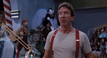 Movie still from “The Santa Clause” (1994), directed by John Pasquin – A man wearing a red suspenders looks upward; Medium shot, Low angle
