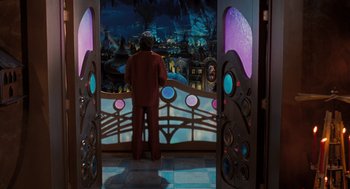Movie still from “The Santa Clause” (1994), directed by John Pasquin – A man standing in front of a window looking out at a city at night; Wide shot, Over the shoulder angle