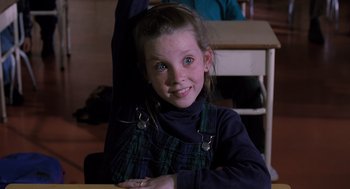 Movie still from “The Santa Clause” (1994), directed by John Pasquin – A young girl sitting at a table smiling for the camera; Close Up shot, High angle