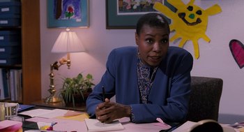 Movie still from “The Santa Clause” (1994), directed by John Pasquin – A woman sitting at a table with a pen and paper; Medium shot, Over the shoulder angle