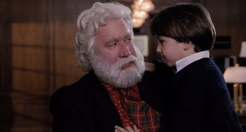 Movie still from “The Santa Clause” (1994), directed by John Pasquin – An old man with a beard and a young boy with a tie; Close Up shot, Over the shoulder angle