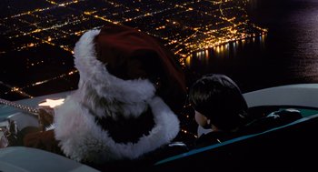 Movie still from “The Santa Clause” (1994), directed by John Pasquin – A man in a santa clause hat sitting in an airplane; Extreme Wide shot, High angle