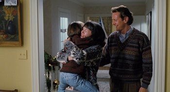 Movie still from “The Santa Clause” (1994), directed by John Pasquin – A woman and a child hug in front of a man and woman; Medium shot, Over the shoulder angle