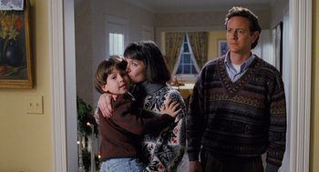 Movie still from “The Santa Clause” (1994), directed by John Pasquin – A woman and a man hug a young boy in front of a house; Medium shot, Over the shoulder angle