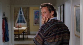 Movie still from “The Santa Clause” (1994), directed by John Pasquin – A man in a sweater is sitting in a living room; Medium shot, Over the shoulder angle