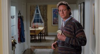 Movie still from “The Santa Clause” (1994), directed by John Pasquin – A man holding a piece of food in his hands; Medium shot, Over the shoulder angle