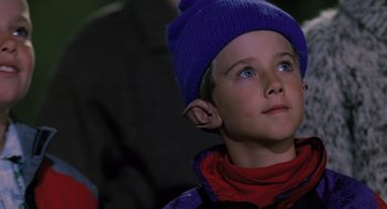 Movie still from “The Santa Clause” (1994), directed by John Pasquin – A young boy wearing a blue hat looking upward; Close Up shot, Low angle