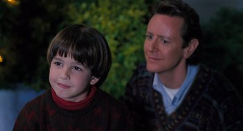 Movie still from “The Santa Clause” (1994), directed by John Pasquin – A man and a boy sitting next to each other in front of a bush; Close Up shot, Over the shoulder angle