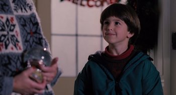 Movie still from “The Santa Clause” (1994), directed by John Pasquin – A young boy is smiling while holding a phone; Medium shot, Over the shoulder angle
