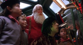 Movie still from “The Santa Clause 2” (2002), directed by Michael Lembeck – A group of children standing next to a man dressed as santa claus; Medium shot, Low angle