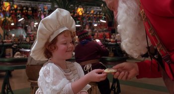 Movie still from “The Santa Clause 2” (2002), directed by Michael Lembeck – A little girl dressed as an old lady handing a piece of food to an old man dressed as santa claus; Close Up shot, Over the shoulder angle