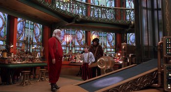 Movie still from “The Santa Clause 2” (2002), directed by Michael Lembeck – A man dressed as santa claus standing in front of two people; Wide shot, High angle
