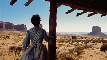 Movie still from “The Searchers” (1956), directed by John Ford – A woman standing in front of an open desert; Wide shot, Low angle