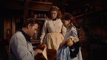Movie still from “The Searchers” (1956), directed by John Ford – A man and two girls standing next to each other in a room; Medium shot, Low angle