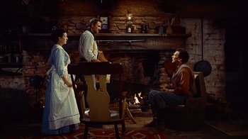 Movie still from “The Searchers” (1956), directed by John Ford – A group of people sitting in front of a fireplace; Wide shot, High angle